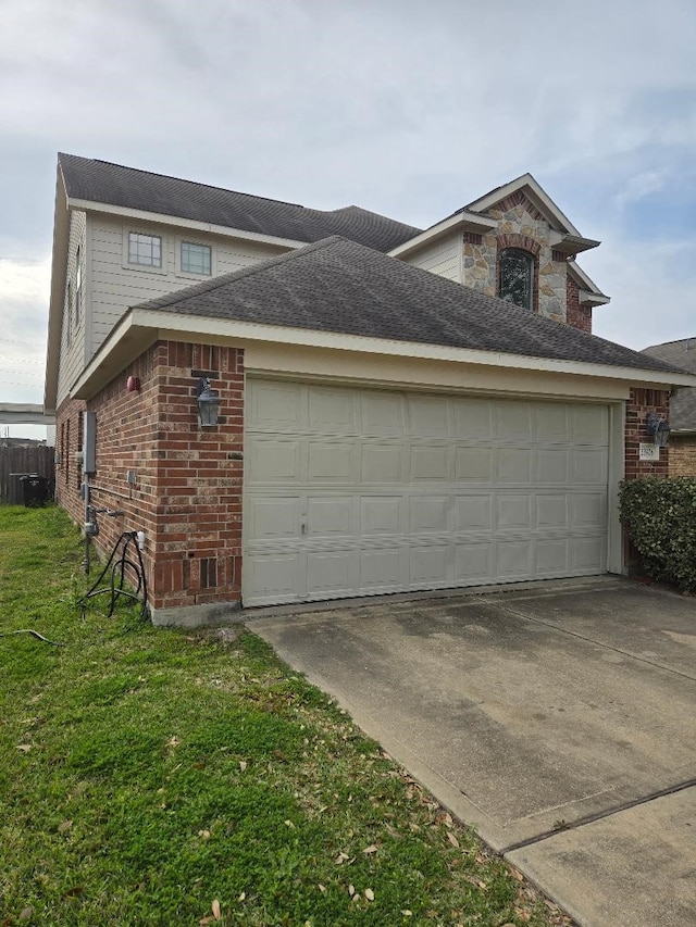 view of side of home with a yard, driveway, brick siding, and an attached garage