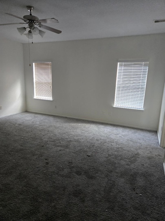 carpeted spare room featuring visible vents, baseboards, a textured ceiling, and a ceiling fan