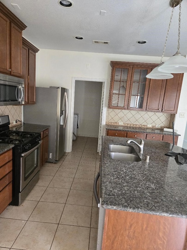 kitchen with light tile patterned floors, visible vents, a sink, glass insert cabinets, and appliances with stainless steel finishes