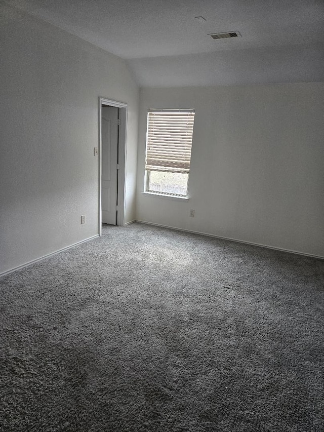 unfurnished room featuring visible vents, lofted ceiling, baseboards, and carpet flooring