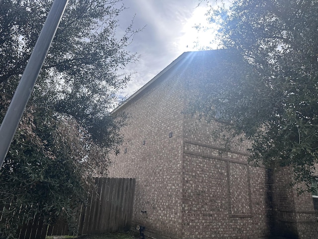 view of property exterior with brick siding and fence