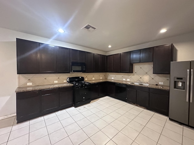 kitchen with tasteful backsplash, visible vents, light stone counters, black appliances, and a sink