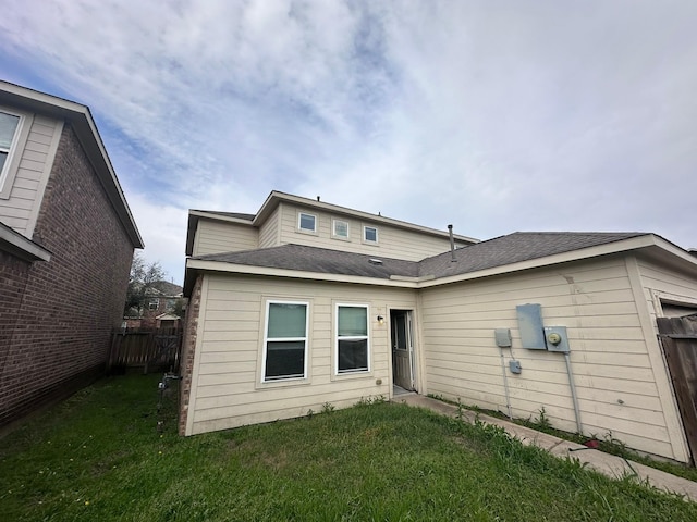 back of house featuring fence and a lawn