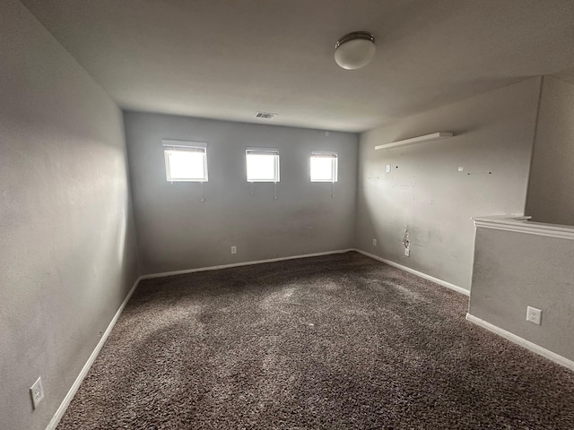 carpeted spare room featuring baseboards, visible vents, and a healthy amount of sunlight