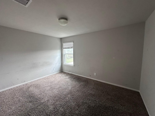 empty room with carpet flooring, visible vents, and baseboards