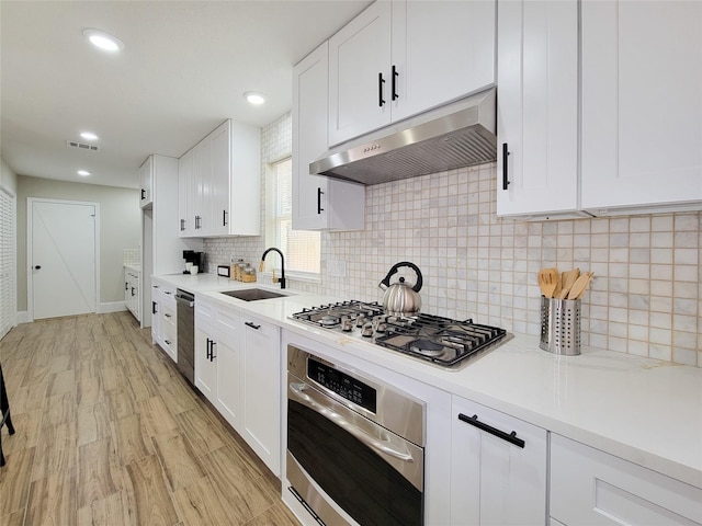 kitchen featuring visible vents, appliances with stainless steel finishes, light countertops, under cabinet range hood, and a sink