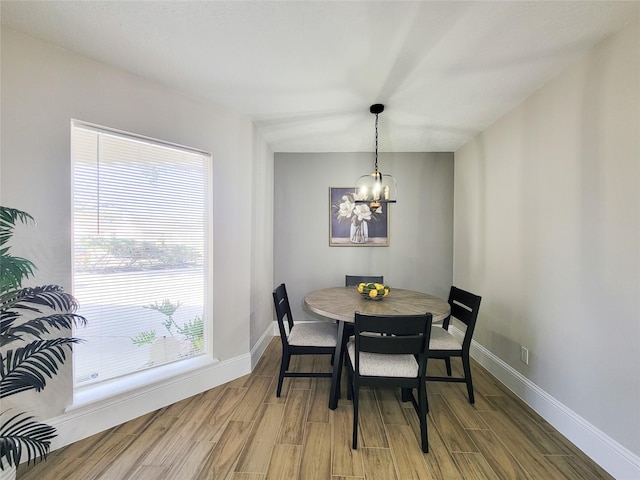 dining space featuring light wood finished floors, an inviting chandelier, and baseboards