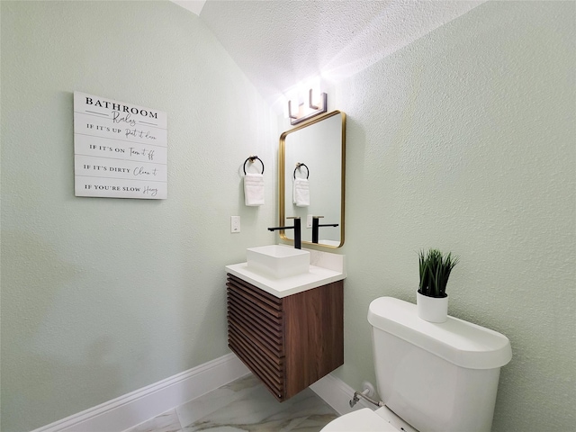 half bath with toilet, marble finish floor, baseboards, and vanity