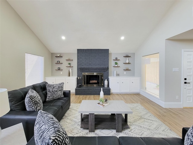 living room featuring baseboards, light wood-style floors, a fireplace, high vaulted ceiling, and recessed lighting