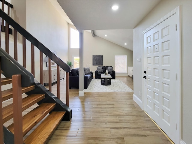 foyer entrance with stairs, high vaulted ceiling, light wood finished floors, and recessed lighting