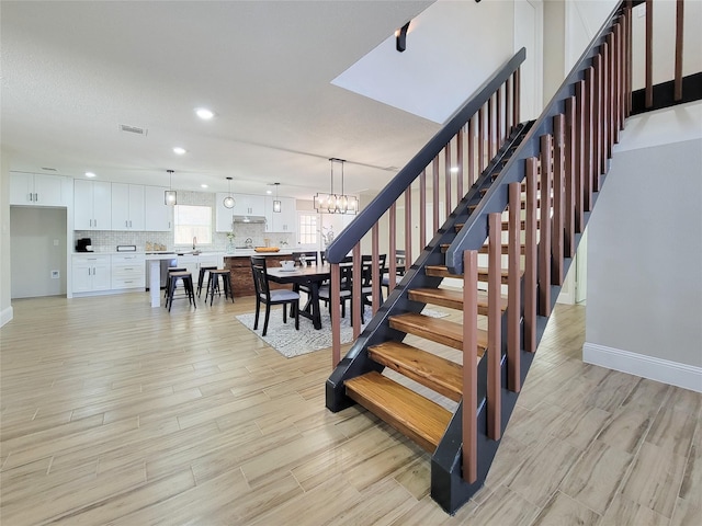 staircase with a chandelier, recessed lighting, visible vents, and wood finished floors