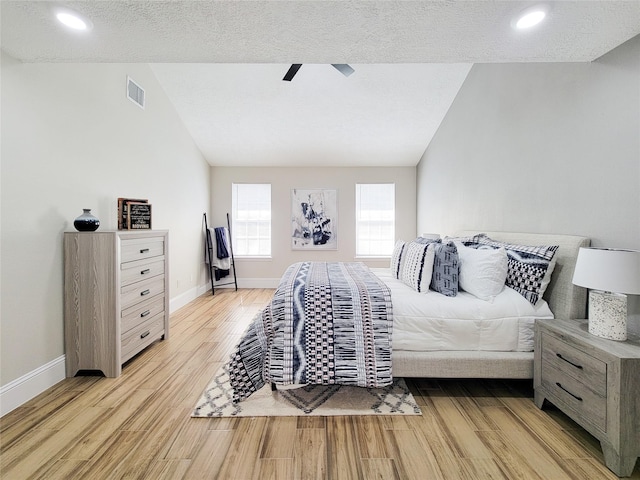 bedroom with lofted ceiling, light wood-style flooring, visible vents, and baseboards