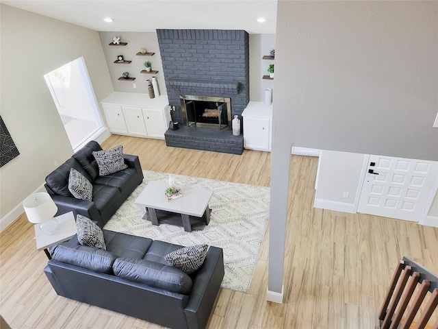 living area with a brick fireplace, baseboards, and wood finished floors