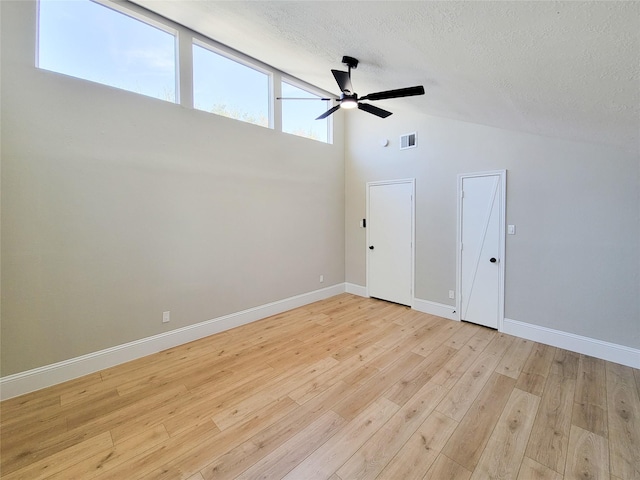 empty room featuring visible vents, light wood-style flooring, ceiling fan, a textured ceiling, and baseboards