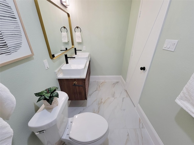 half bathroom with marble finish floor, vanity, toilet, and baseboards