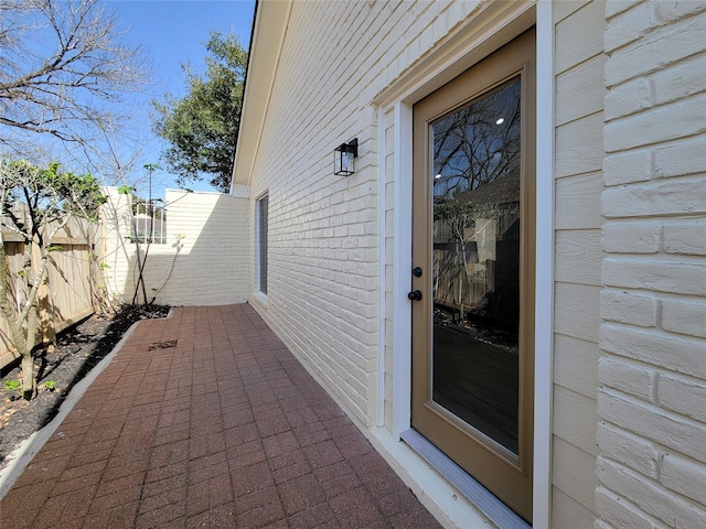 entrance to property with a patio area, fence, and brick siding