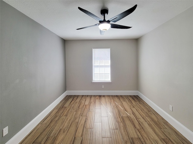 spare room featuring ceiling fan, a textured ceiling, baseboards, and wood finished floors