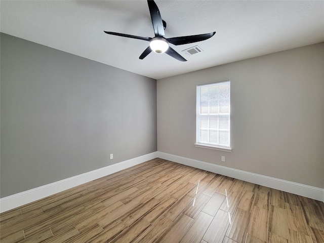 unfurnished room featuring a textured ceiling, wood finished floors, a ceiling fan, visible vents, and baseboards