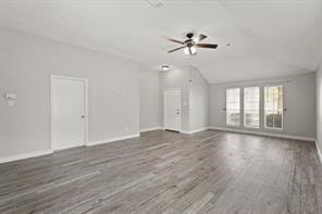 unfurnished living room with lofted ceiling, wood finished floors, a ceiling fan, and baseboards