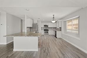 kitchen featuring stove, white cabinets, wood finished floors, and freestanding refrigerator