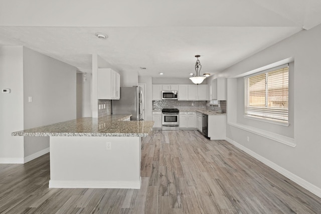 kitchen with a peninsula, white cabinetry, appliances with stainless steel finishes, and decorative backsplash