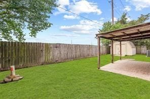 view of yard featuring an outbuilding, a patio, a shed, a fenced backyard, and driveway