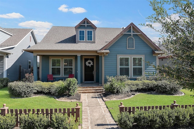 view of front of house with a shingled roof and a front lawn