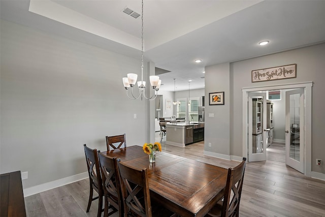 dining area featuring french doors, a notable chandelier, visible vents, light wood-style flooring, and baseboards