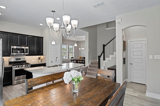 dining space featuring arched walkways, visible vents, stairway, light wood-style floors, and a notable chandelier