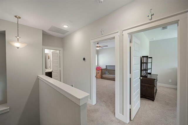 hall featuring light carpet, visible vents, and an upstairs landing