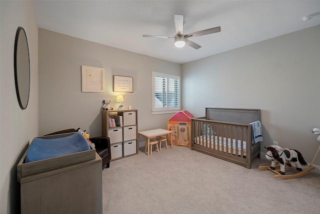 bedroom featuring carpet floors, a nursery area, and a ceiling fan