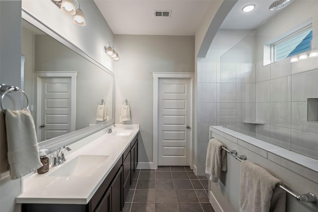 full bathroom featuring walk in shower, a sink, visible vents, and tile patterned floors