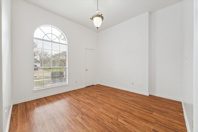 spare room featuring baseboards and wood finished floors