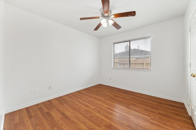 empty room featuring wood finished floors, a ceiling fan, and baseboards