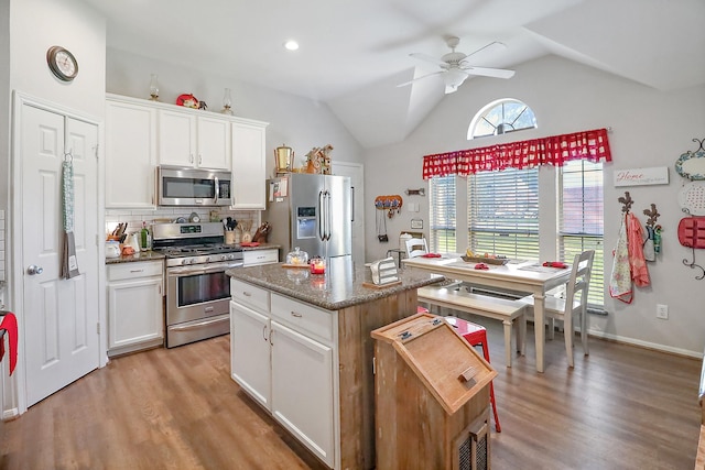 kitchen with a center island with sink, light wood finished floors, stainless steel appliances, decorative backsplash, and white cabinets