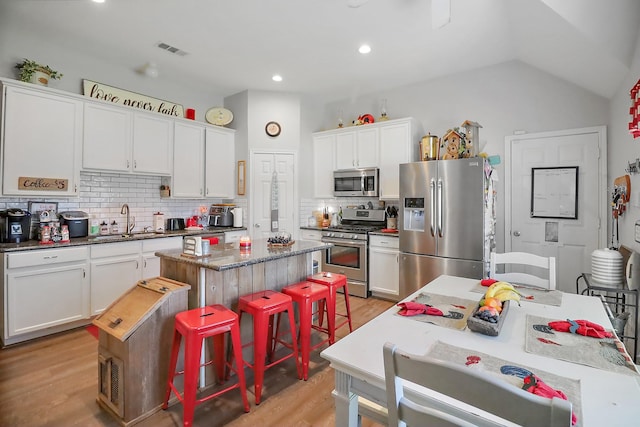 kitchen with a center island, stainless steel appliances, visible vents, white cabinets, and a sink