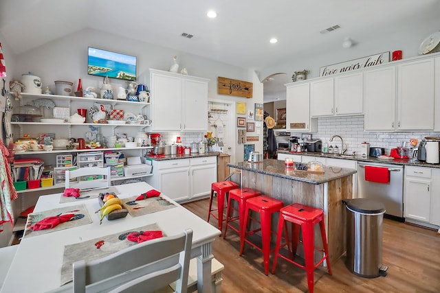 kitchen with visible vents, white cabinets, a kitchen island, wood finished floors, and stainless steel dishwasher