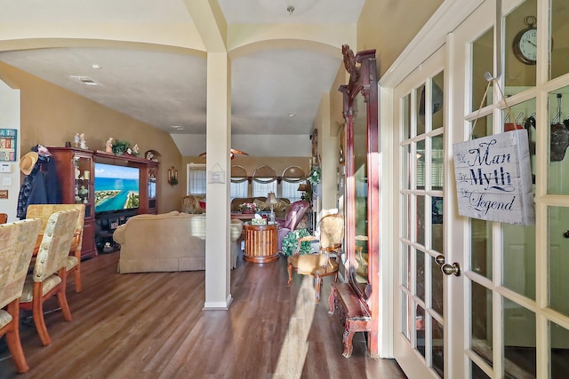 foyer entrance with arched walkways, vaulted ceiling, wood finished floors, and visible vents