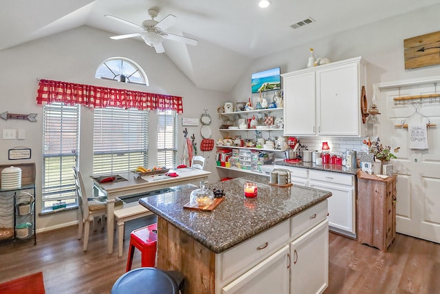 kitchen with lofted ceiling, backsplash, a ceiling fan, white cabinets, and wood finished floors