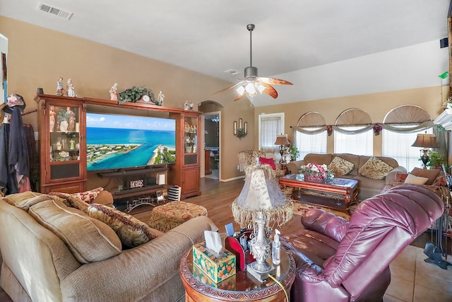 living area with a ceiling fan, arched walkways, visible vents, and lofted ceiling