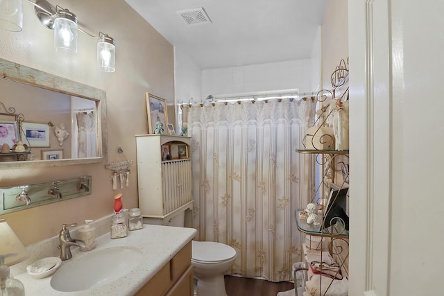 bathroom with toilet, a shower with curtain, visible vents, and vanity