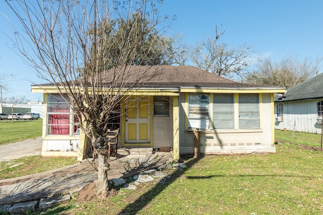 bungalow-style house featuring a shingled roof and a front yard