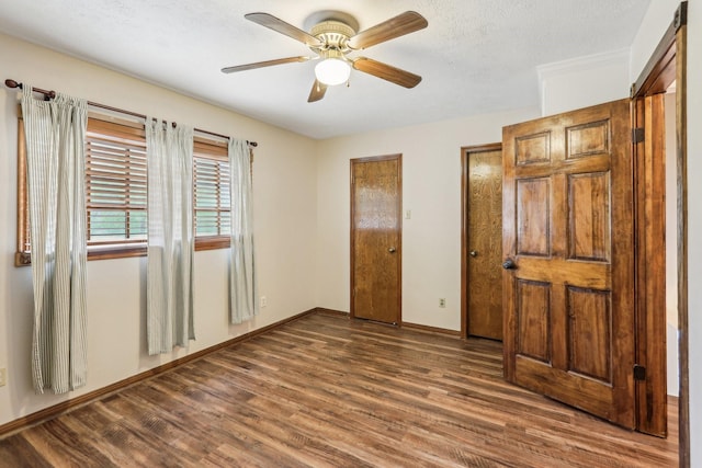5503 Bayou Blvd, Baytown, TX 77521 - unfurnished bedroom with baseboards, a textured ceiling, dark wood-style floors, and multiple closets