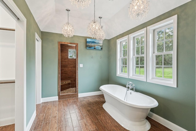 5503 Bayou Blvd, Baytown, TX 77521 - bathroom featuring baseboards, wood finished floors, vaulted ceiling, a freestanding tub, and a notable chandelier