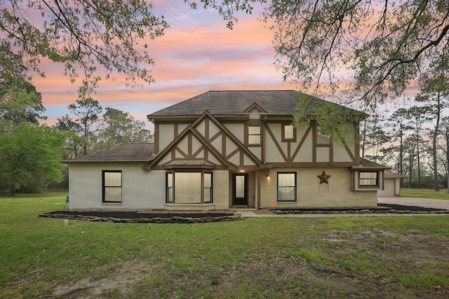5503 Bayou Blvd, Baytown, TX 77521 - tudor-style house featuring a garage, a lawn, brick siding, and a shingled roof