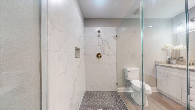 bathroom with visible vents, a shower, toilet, wood finished floors, and vanity