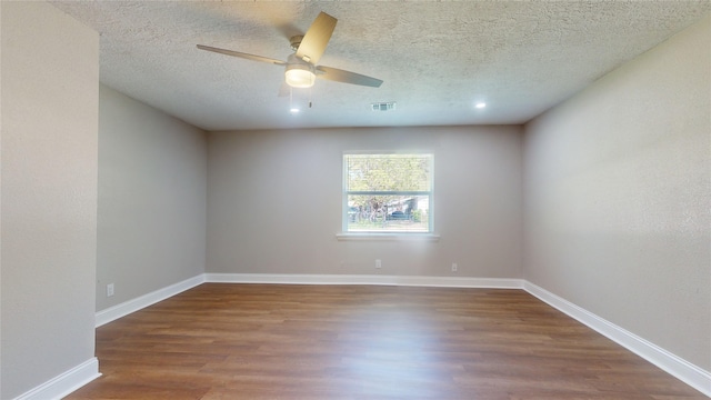 unfurnished room featuring visible vents, a textured ceiling, baseboards, and wood finished floors