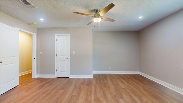 empty room with baseboards, visible vents, ceiling fan, a textured ceiling, and light wood-style floors