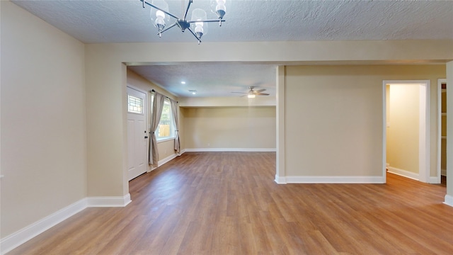 empty room featuring a textured ceiling, wood finished floors, and baseboards