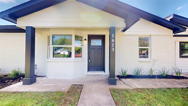 doorway to property featuring brick siding